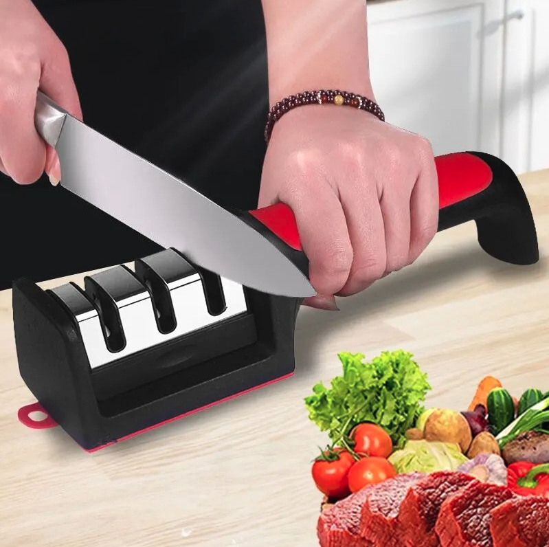 Afilador de cuchillos 3 en 1 en uso, afilando un cuchillo en cocina con vegetales frescos en la mesa