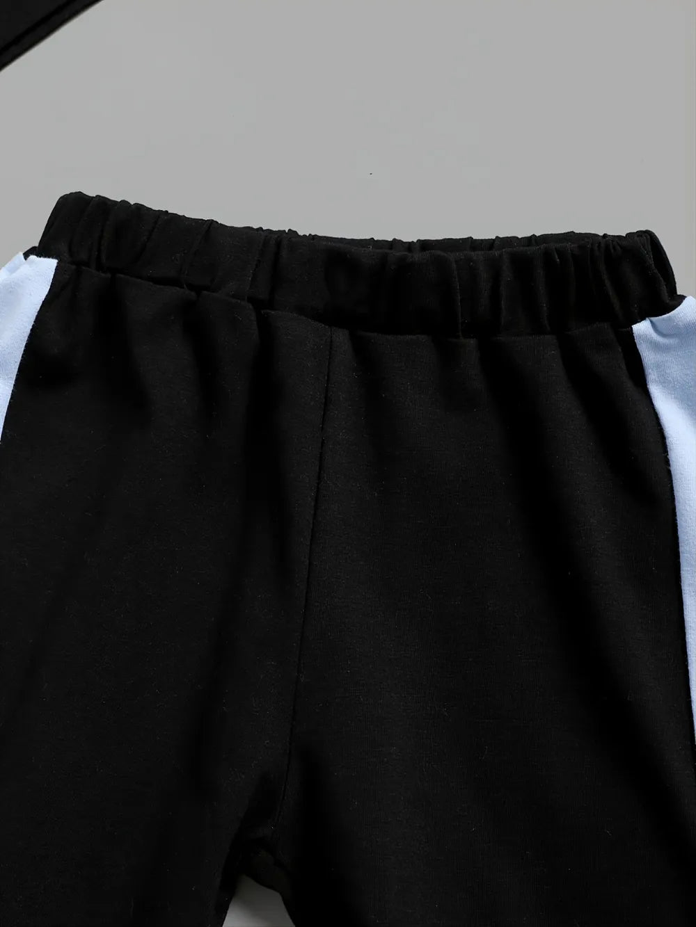 Conjunto infantil bloque de color con pantalones negros y detalles en azul claro, suave y cómodo